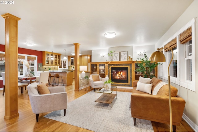 living room with light hardwood / wood-style floors, ornate columns, and sink