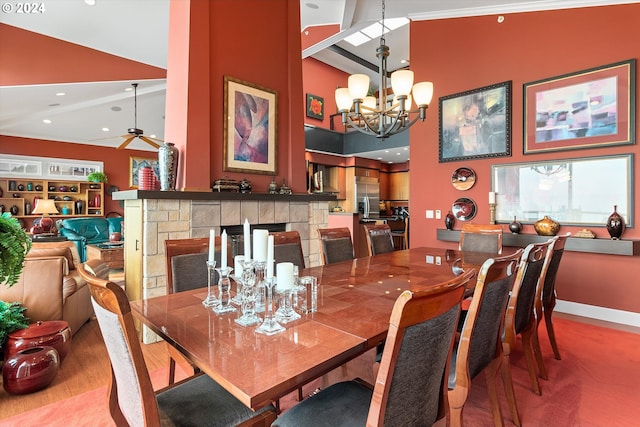 dining room featuring a towering ceiling, baseboards, a stone fireplace, recessed lighting, and a chandelier