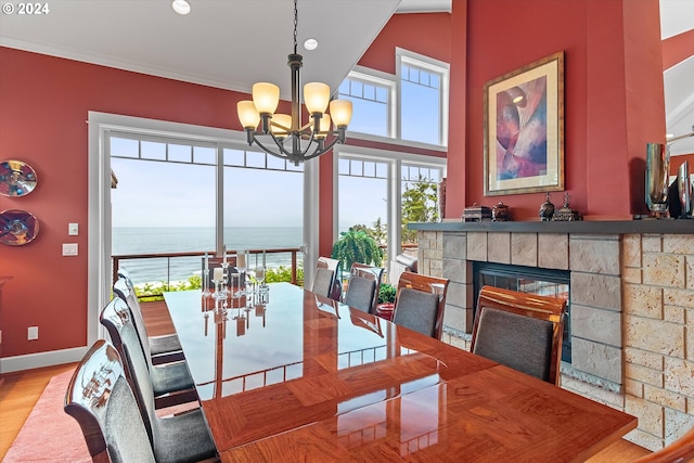 dining room featuring wood finished floors, baseboards, a notable chandelier, a glass covered fireplace, and recessed lighting
