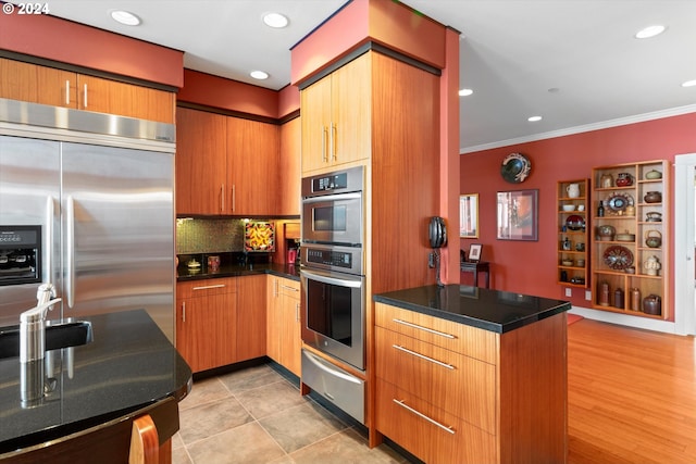 kitchen with crown molding, dark countertops, appliances with stainless steel finishes, decorative backsplash, and a warming drawer