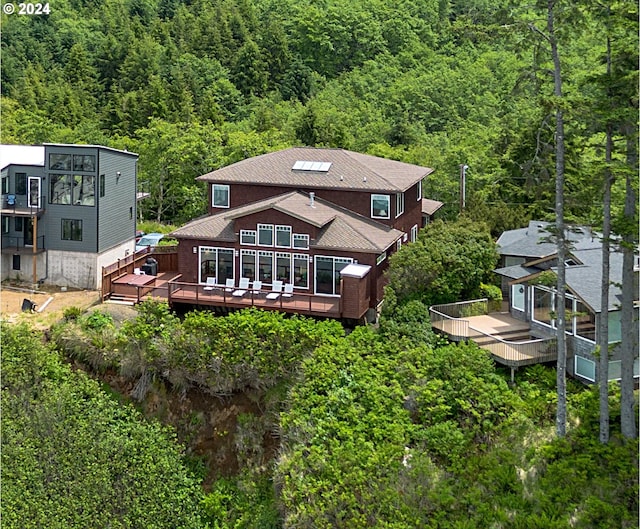 back of property featuring a view of trees and a deck