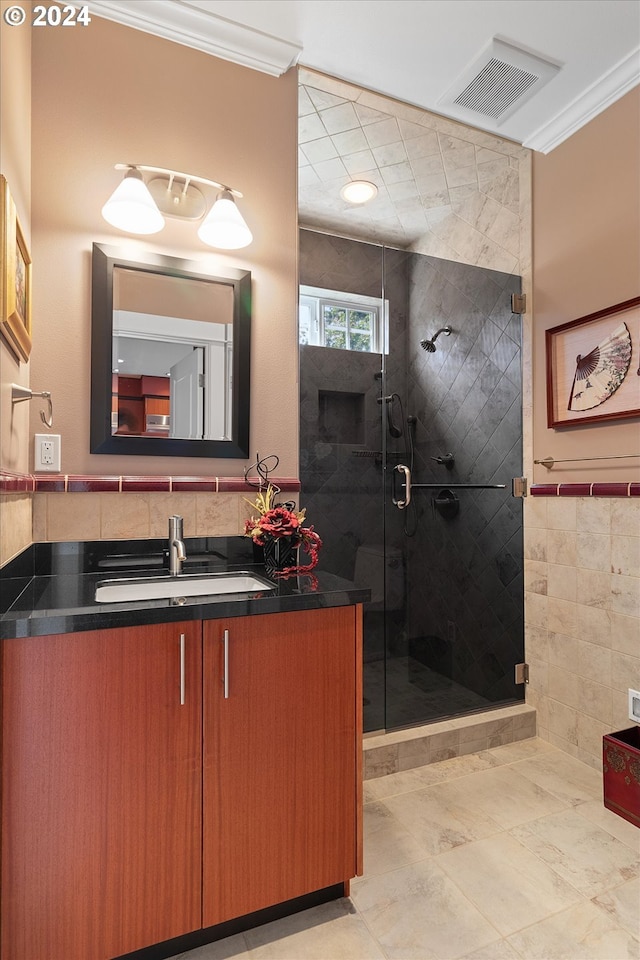full bath with crown molding, vanity, tile walls, a shower stall, and visible vents