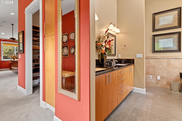 bathroom with ceiling fan, tile walls, vanity, baseboards, and recessed lighting