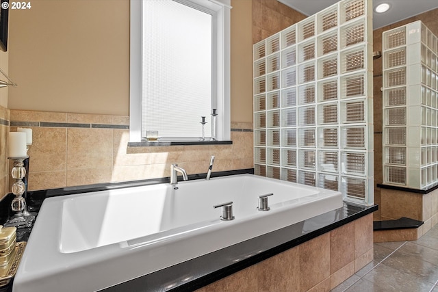 bathroom featuring tile patterned floors, a bath, and tile walls