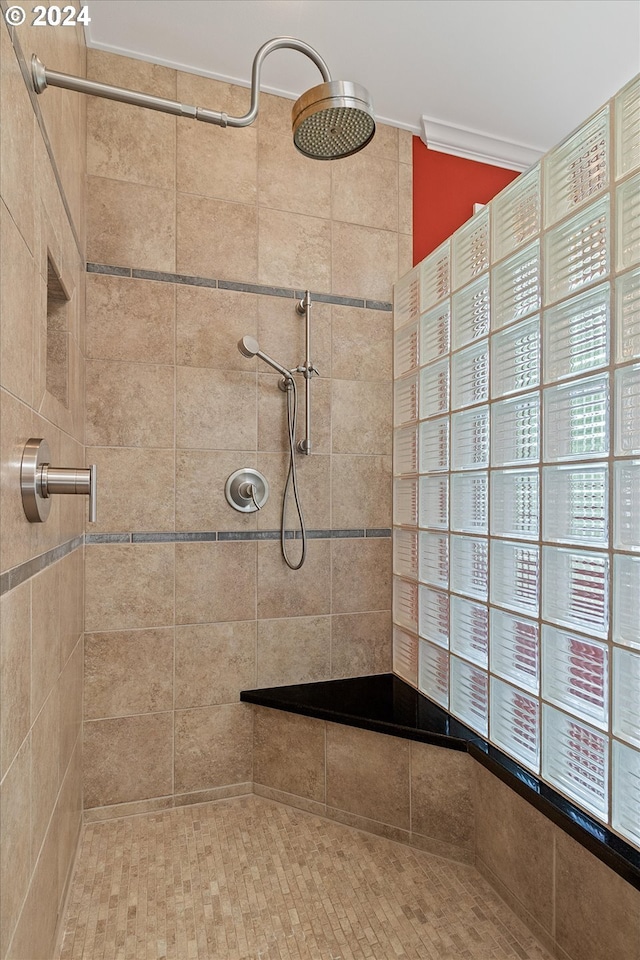 bathroom with ornamental molding and tiled shower