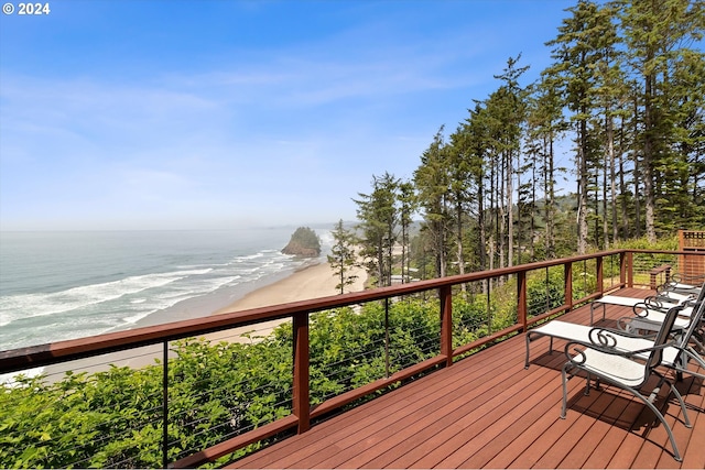 wooden deck featuring a view of the beach and a water view