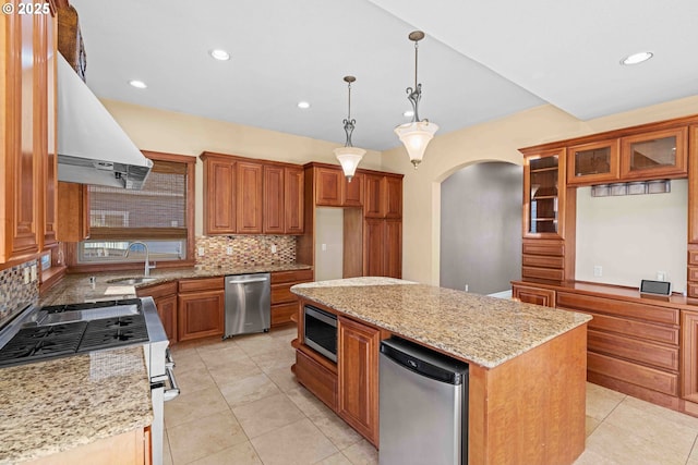 kitchen featuring light stone counters, a center island, stainless steel appliances, and sink