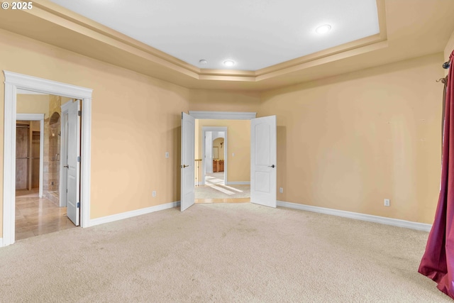 carpeted spare room with a raised ceiling