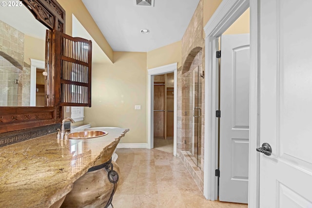 bathroom featuring a shower with door and sink