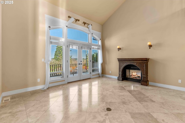 unfurnished living room featuring light tile patterned floors, high vaulted ceiling, and french doors