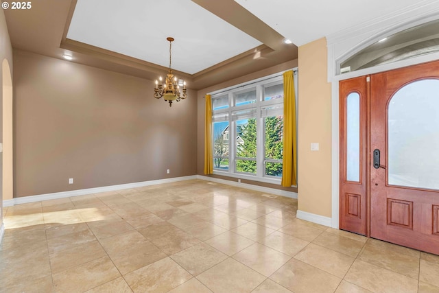 foyer entrance featuring light tile patterned floors, a tray ceiling, and an inviting chandelier