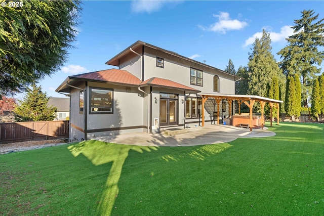 rear view of property featuring a yard, a patio, and a hot tub