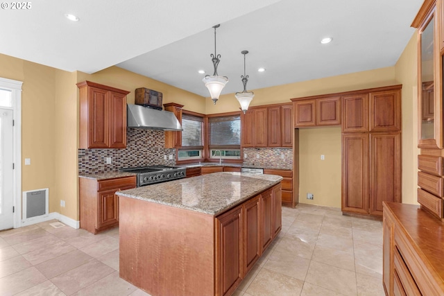 kitchen featuring pendant lighting, a center island, stainless steel range, light stone counters, and extractor fan