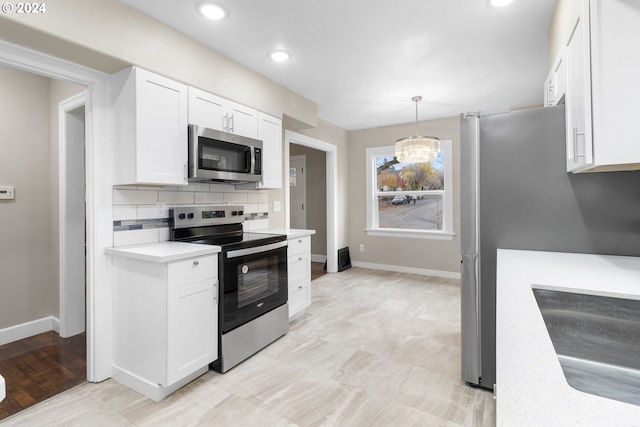 kitchen with white cabinets, hanging light fixtures, appliances with stainless steel finishes, and sink