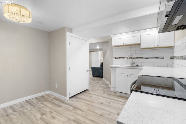 kitchen featuring exhaust hood, white cabinetry, decorative backsplash, and sink