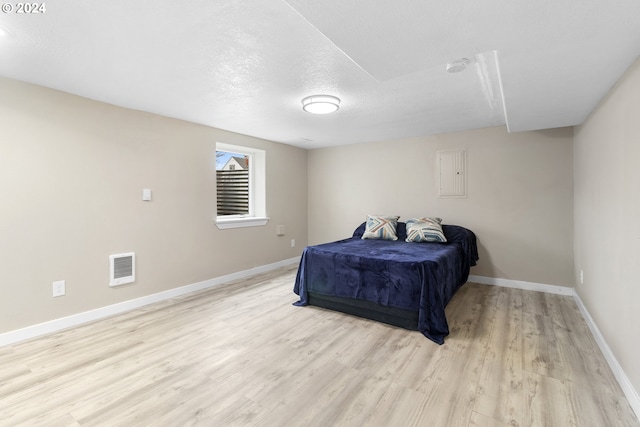 bedroom with a textured ceiling and light wood-type flooring