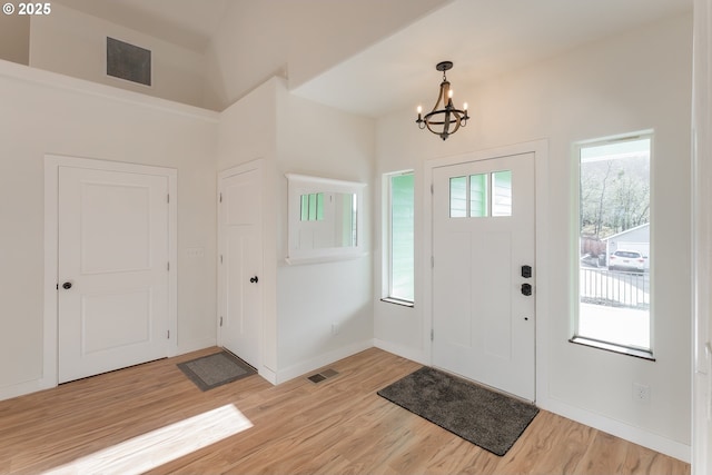 entryway with a notable chandelier, plenty of natural light, and light hardwood / wood-style flooring