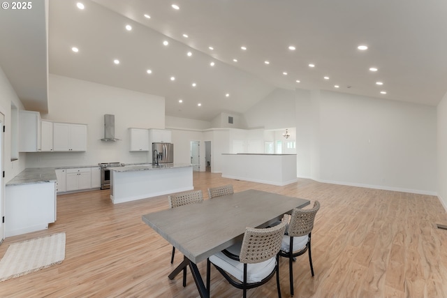 dining area with light hardwood / wood-style floors and high vaulted ceiling