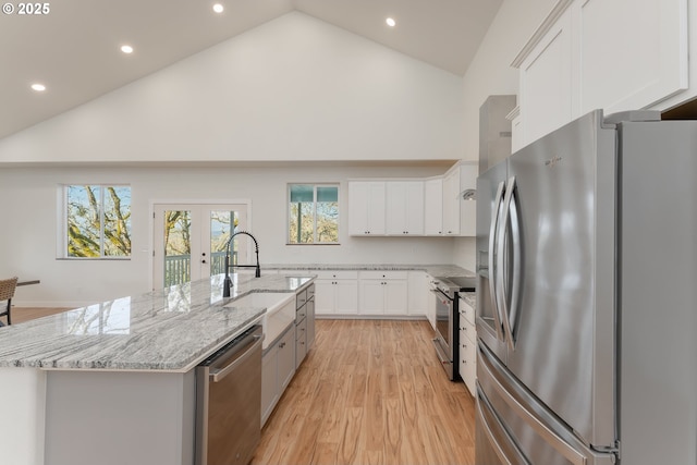 kitchen featuring white cabinetry, stainless steel appliances, high vaulted ceiling, and an island with sink