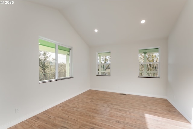 empty room featuring vaulted ceiling, light hardwood / wood-style flooring, and a healthy amount of sunlight