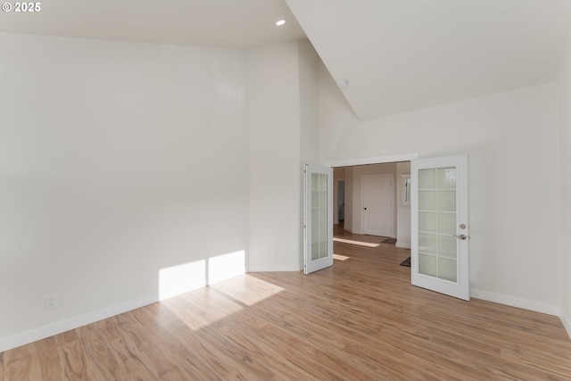 spare room with light hardwood / wood-style flooring, high vaulted ceiling, and french doors