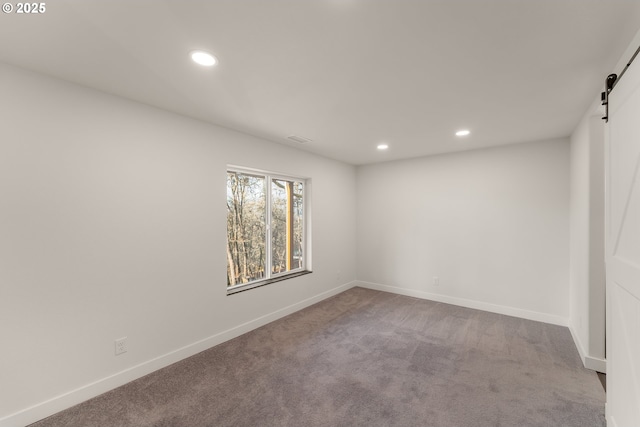 carpeted empty room with a barn door