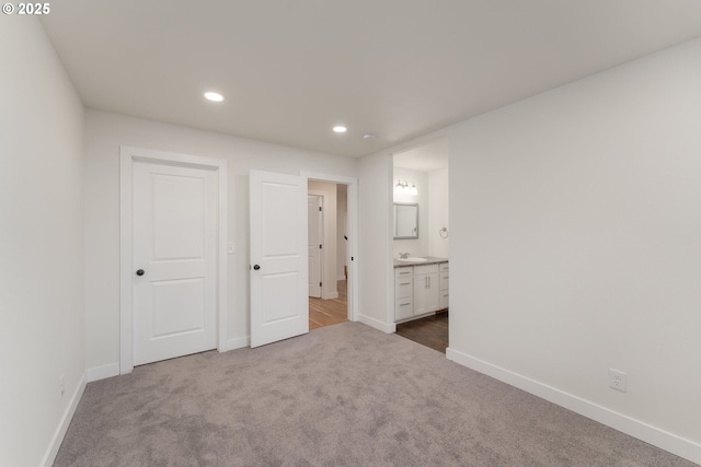 unfurnished bedroom with carpet floors, ensuite bath, and sink