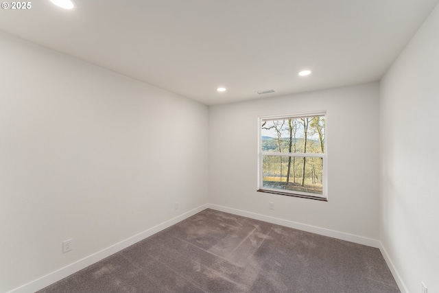 unfurnished room featuring dark colored carpet