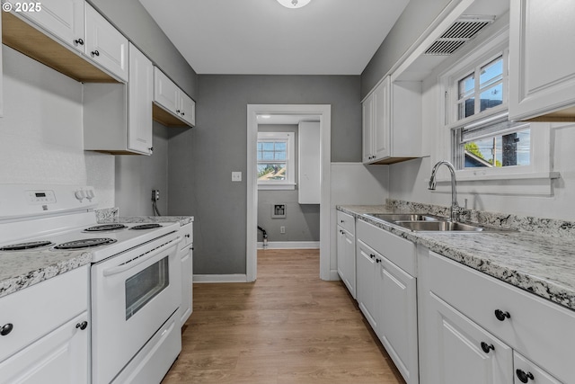 2849 Florida St, Longview, WA 98632 - kitchen featuring white electric range, white cabinetry, light wood-style flooring, and healthy amount of natural light