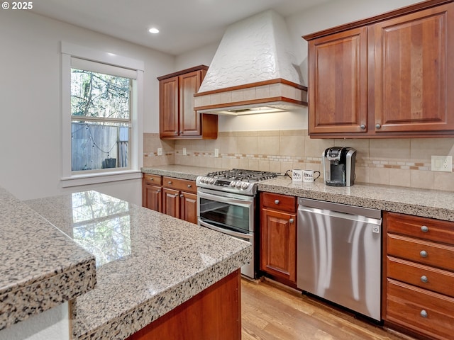 kitchen featuring light hardwood / wood-style flooring, backsplash, custom exhaust hood, and stainless steel appliances