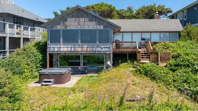 rear view of house with a hot tub and a deck