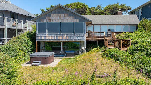 rear view of house with a hot tub and a deck