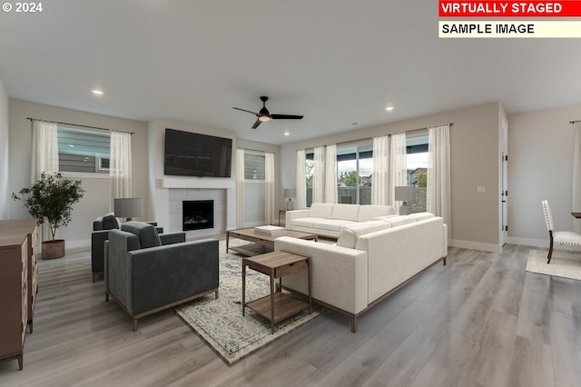 living room featuring light wood-type flooring, a tile fireplace, and ceiling fan