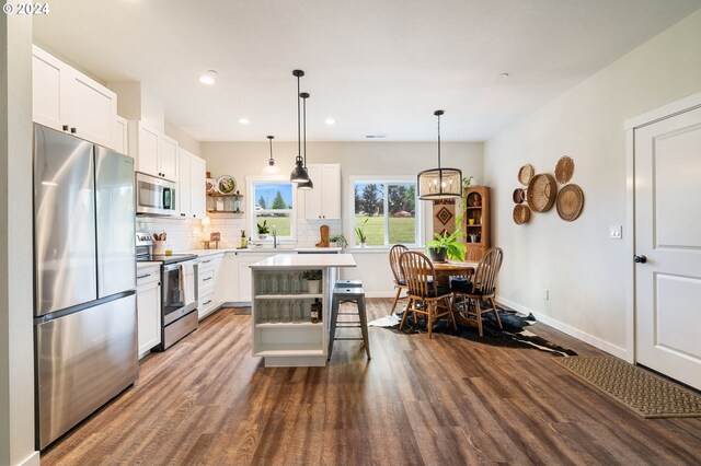 kitchen with stainless steel appliances, a kitchen island, dark hardwood / wood-style flooring, a breakfast bar area, and white cabinets