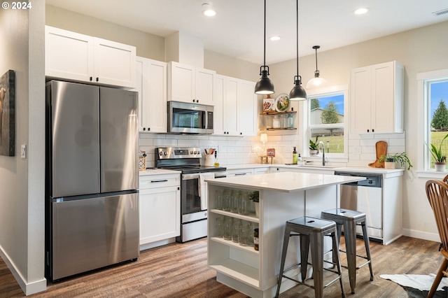 kitchen featuring sink, a kitchen island, a kitchen bar, white cabinetry, and stainless steel appliances