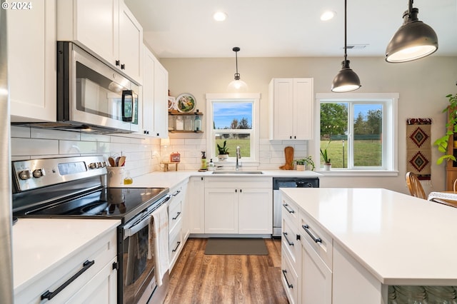 kitchen with plenty of natural light, white cabinetry, hanging light fixtures, and appliances with stainless steel finishes