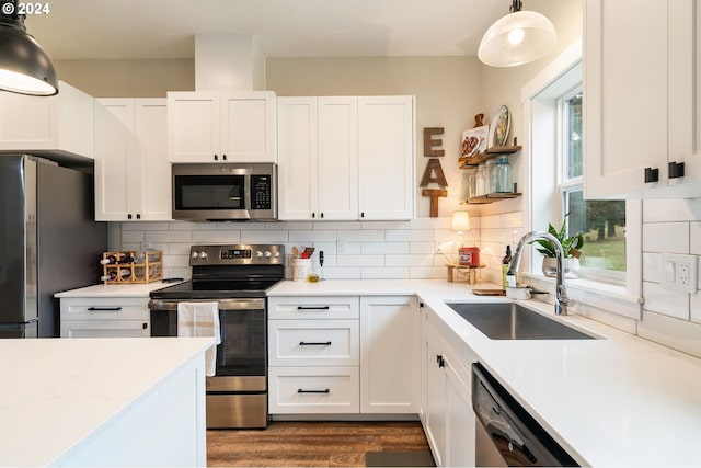 kitchen featuring decorative light fixtures, stainless steel appliances, white cabinetry, and sink