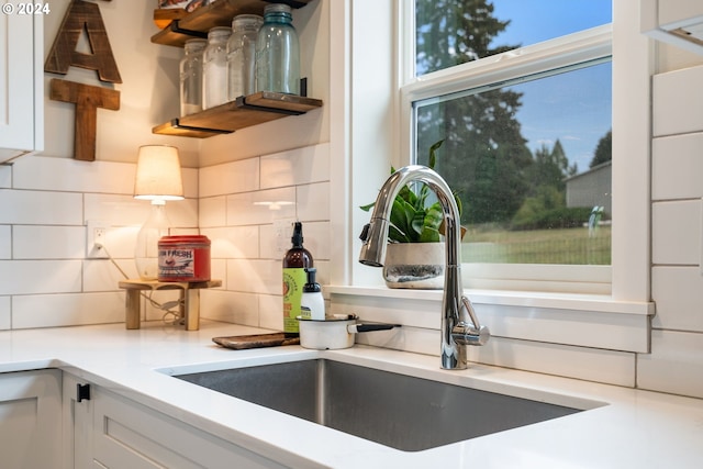 kitchen with white cabinets, backsplash, and sink