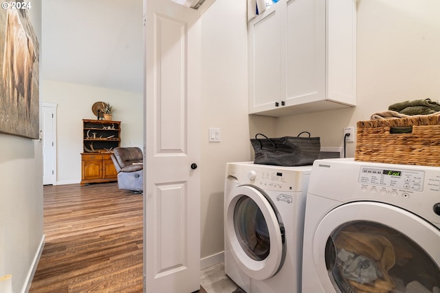 washroom with cabinets, washing machine and dryer, and hardwood / wood-style flooring