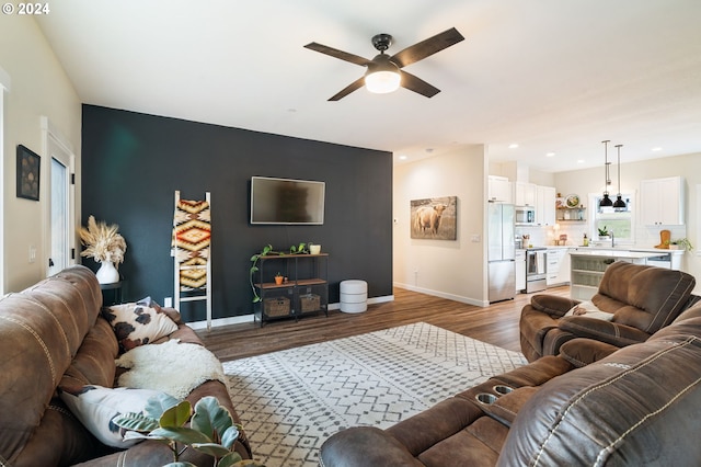 living room with hardwood / wood-style flooring, ceiling fan, and sink