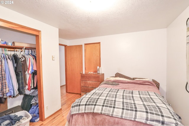 bedroom featuring a closet, light wood-style flooring, and a textured ceiling