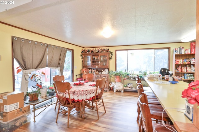 dining room featuring a healthy amount of sunlight, ornamental molding, and wood finished floors