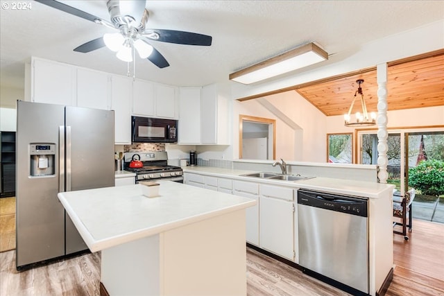 kitchen featuring appliances with stainless steel finishes, a kitchen island, white cabinetry, sink, and hanging light fixtures