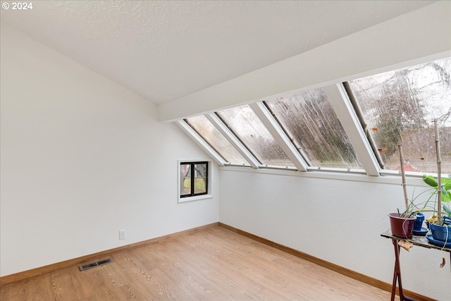 bonus room with vaulted ceiling and light hardwood / wood-style flooring