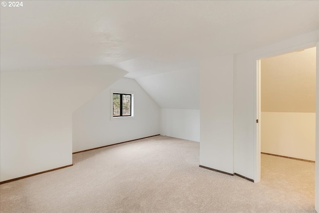 bonus room with light carpet and vaulted ceiling