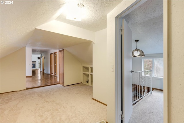 bonus room featuring lofted ceiling, light colored carpet, a textured ceiling, and built in shelves