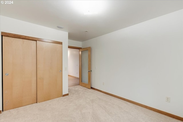 unfurnished bedroom featuring a closet and light carpet