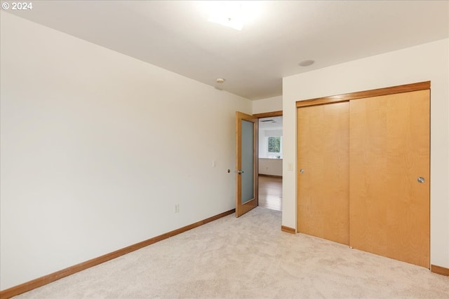 unfurnished bedroom featuring a closet and light colored carpet