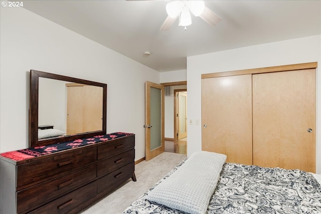 bedroom with ceiling fan, light colored carpet, and a closet