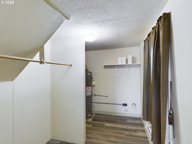 laundry area featuring a textured ceiling, electric water heater, a baseboard heating unit, and dark wood-type flooring